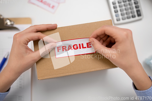 Image of woman sticking fragile mark to parcel box