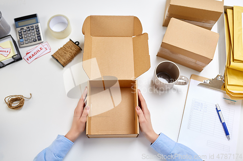 Image of hands with empty parcel box and mug at post office