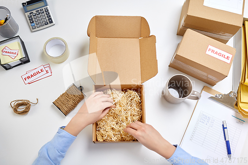 Image of hands with straw filler in parcel at post office