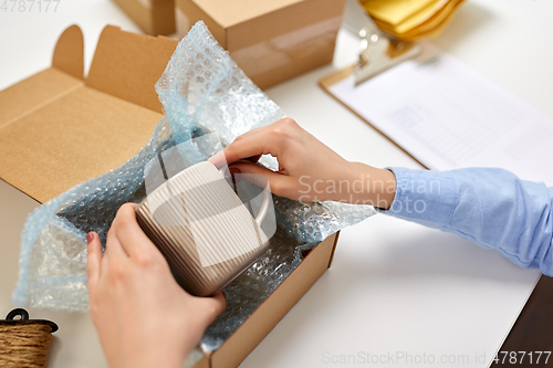 Image of hands packing mug to parcel box at post office