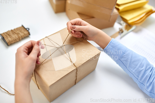 Image of hands packing parcel and tying rope at post office