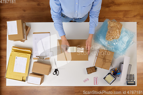 Image of woman packing parcel box with adhesive tape