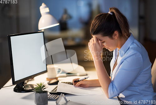 Image of businesswoman with papers working at night office