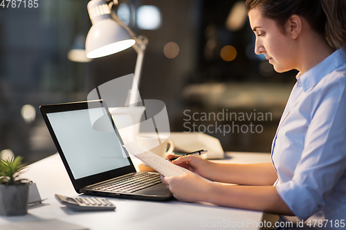 Image of businesswoman with papers working at night office