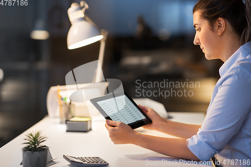 Image of businesswoman with tablet computer at night office