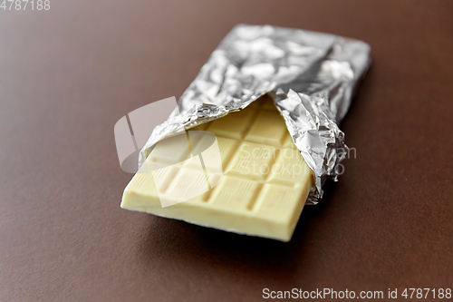 Image of white chocolate bar in foil wrapper on brown