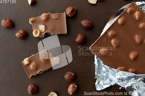Image of milk chocolate bar with hazelnuts in foil wrapper
