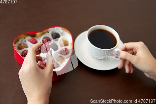 Image of hands, candies in heart shaped box and coffee cup