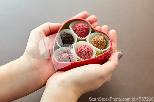 Image of hands with candies in heart shaped chocolate box
