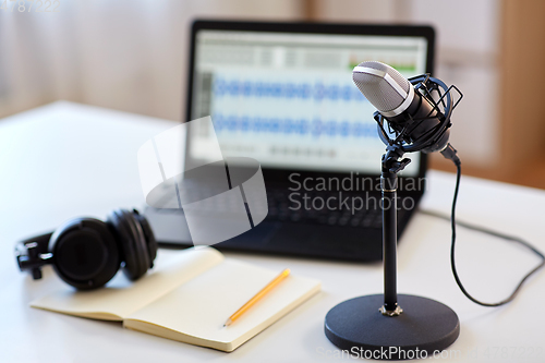 Image of microphone, laptop, headphones, notebook on table