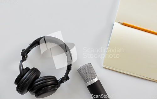 Image of headphones, microphone and notebook with pencil