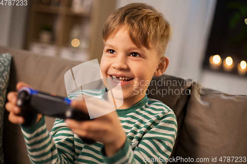 Image of little boy with gamepad playing video game at home