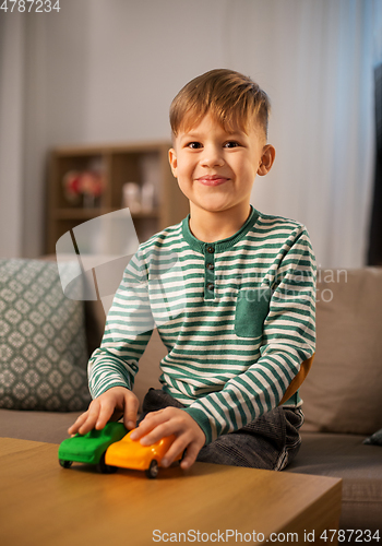 Image of happy little boy playing with toy cars at home