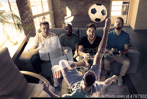 Image of Group of excited friends playing video games at home