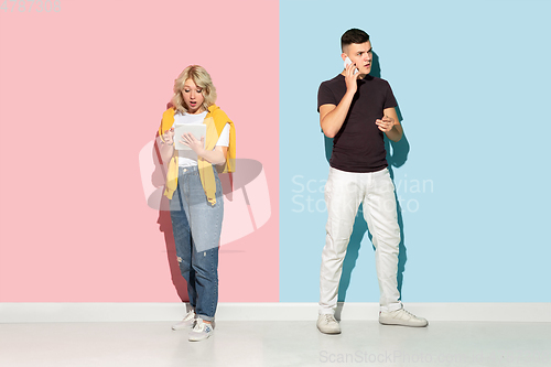 Image of Young emotional man and woman on pink and blue background