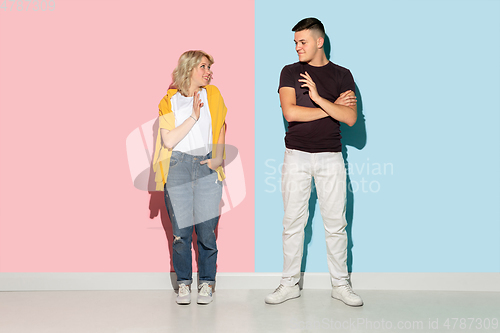 Image of Young emotional man and woman on pink and blue background