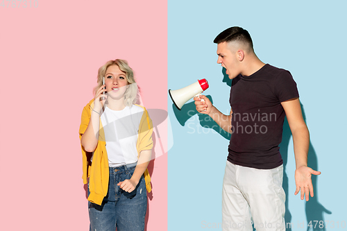 Image of Young emotional man and woman on pink and blue background