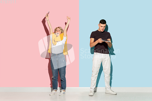 Image of Young emotional man and woman on pink and blue background