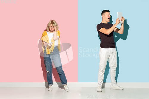 Image of Young emotional man and woman on pink and blue background