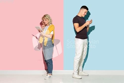 Image of Young emotional man and woman on pink and blue background