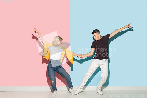 Image of Young emotional man and woman on pink and blue background
