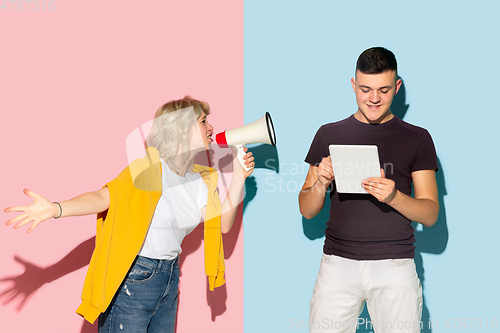 Image of Young emotional man and woman on pink and blue background