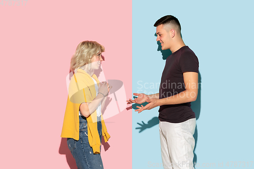 Image of Young emotional man and woman on pink and blue background