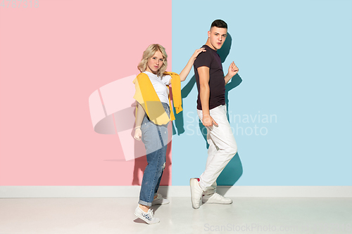 Image of Young emotional man and woman on pink and blue background