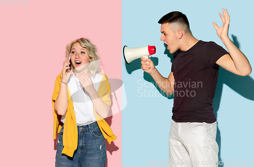 Image of Young emotional man and woman on pink and blue background