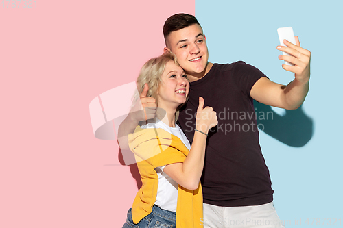 Image of Young emotional man and woman on pink and blue background