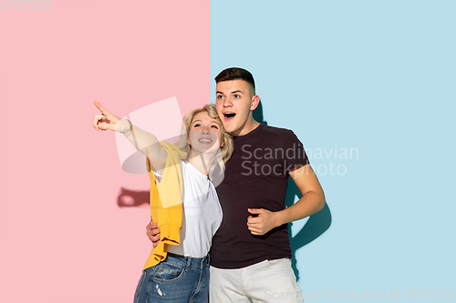 Image of Young emotional man and woman on pink and blue background
