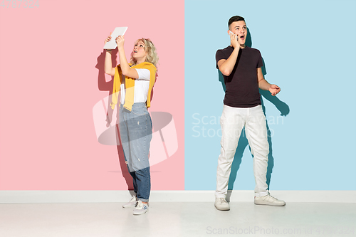 Image of Young emotional man and woman on pink and blue background