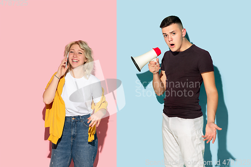 Image of Young emotional man and woman on pink and blue background