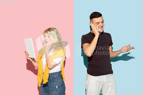 Image of Young emotional man and woman on pink and blue background