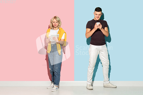 Image of Young emotional man and woman on pink and blue background