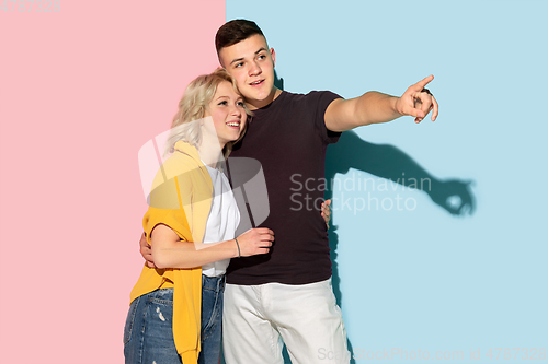 Image of Young emotional man and woman on pink and blue background