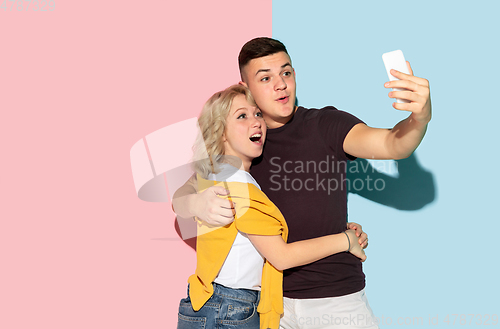 Image of Young emotional man and woman on pink and blue background