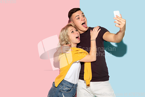 Image of Young emotional man and woman on pink and blue background