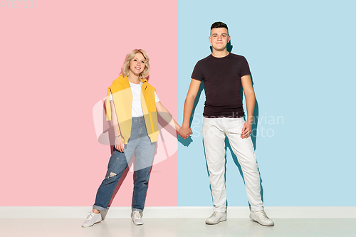 Image of Young emotional man and woman on pink and blue background