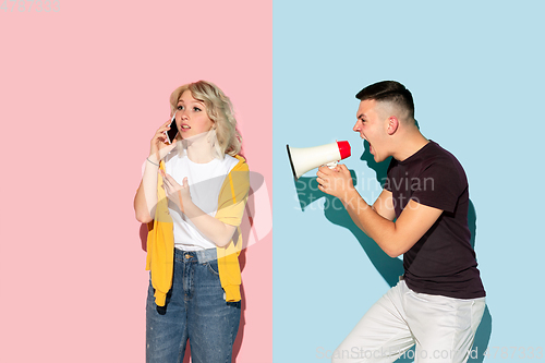 Image of Young emotional man and woman on pink and blue background