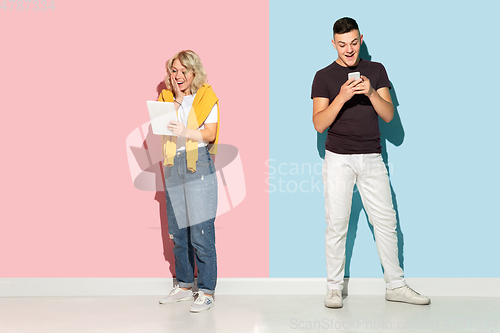Image of Young emotional man and woman on pink and blue background