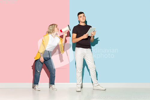 Image of Young emotional man and woman on pink and blue background