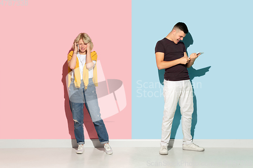 Image of Young emotional man and woman on pink and blue background