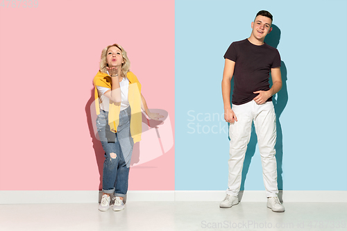 Image of Young emotional man and woman on pink and blue background
