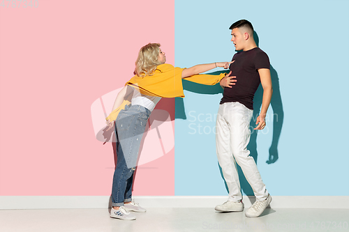 Image of Young emotional man and woman on pink and blue background