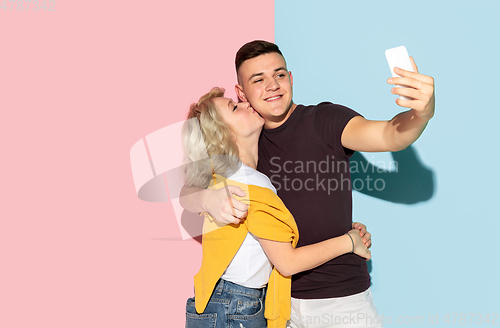Image of Young emotional man and woman on pink and blue background
