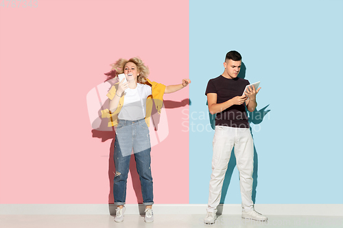 Image of Young emotional man and woman on pink and blue background