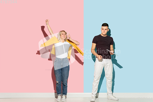 Image of Young emotional man and woman on pink and blue background