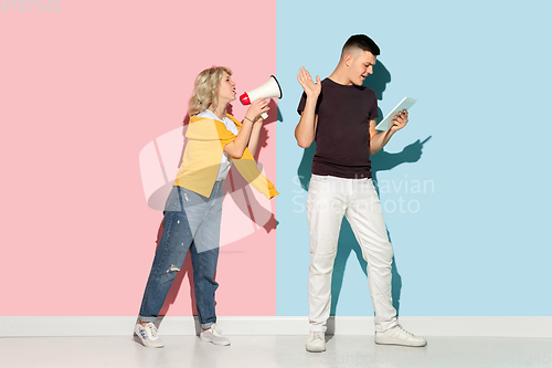 Image of Young emotional man and woman on pink and blue background