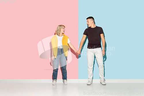 Image of Young emotional man and woman on pink and blue background